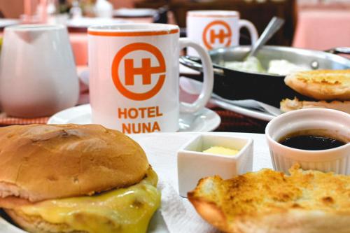 a breakfast plate with a sandwich and a cup of coffee at HOTEL NUNA in Puerto Montt
