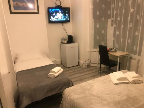 a room with two beds and a tv on the wall at En Suite Double Room 2 in Plumstead