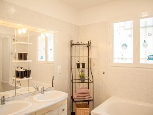 een witte badkamer met 2 wastafels en een spiegel bij Loustalet Plus in Bagnols-en-Forêt