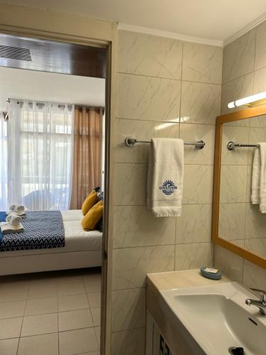 ein Bad mit einem Bett, einem Waschbecken und einem Spiegel in der Unterkunft SUNSTUDIO TARIK AL in Portimão