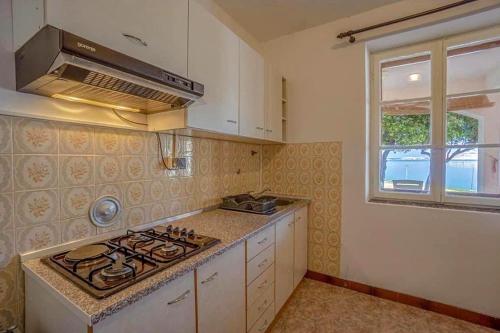 a kitchen with a stove top oven next to a window at Apartments by the sea Metajna, Pag - 6465 in Metajna