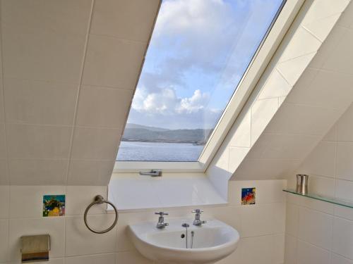 a skylight in a bathroom with a sink and a window at Macneils Croft in Gortenfern