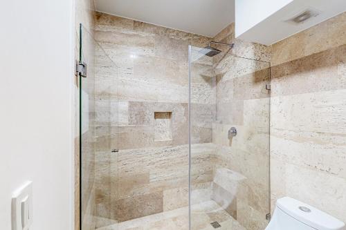 a bathroom with a glass shower with a toilet at Menesse Midtown 2 Unit 208 in Playa del Carmen