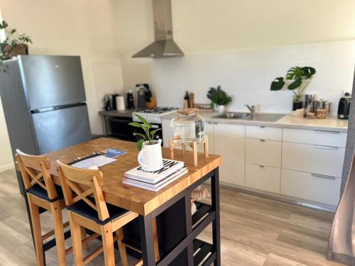 a kitchen with a wooden table with chairs and a refrigerator at Serenity in Style in Kalbarri