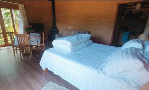 a bedroom with a large bed with pillows on it at Chalé Caminho do Paiol in São Bento do Sapucaí