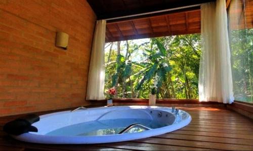 a large tub in a room with a large window at Chalé Caminho do Paiol in São Bento do Sapucaí