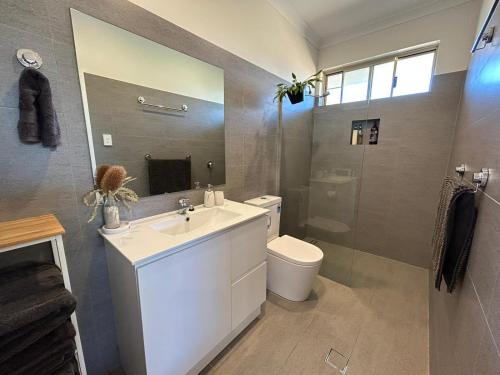 a bathroom with a sink and a toilet and a mirror at Serenity in Style in Kalbarri