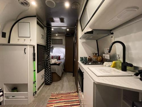 una cocina con fregadero y un dormitorio en Airstream Caravel 2020 Loblolly Pines Adventure Camp en Eureka Springs