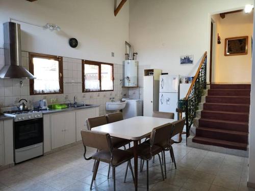 a kitchen with a table and chairs and a staircase at Amplia casa con estacionamiento in Esquel