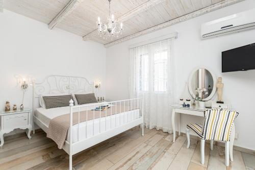 a white bedroom with a bed and a desk and a mirror at Villa Nektar, Luxury Apartment in Chora Naxos in Naxos Chora