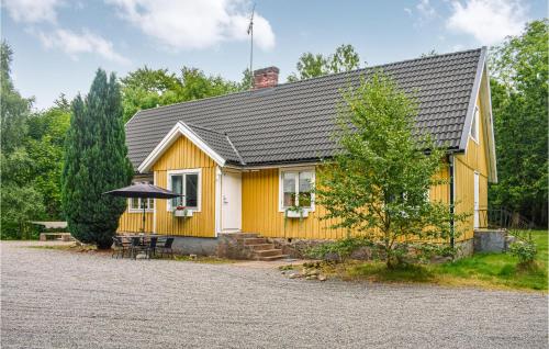 a yellow house with a table and an umbrella at 7 Bedroom Awesome Home In Örkelljunga in Orkelljunga