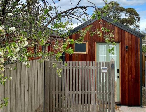 Belmont的住宿－Stylish Geelong Cabin - Your home away from home，一座红色的房子,有栅栏和门