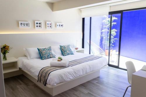 Un dormitorio con una cama con una ventana grande. en Dazzling house in the heart of Coyoacan/12 guests, en Ciudad de México