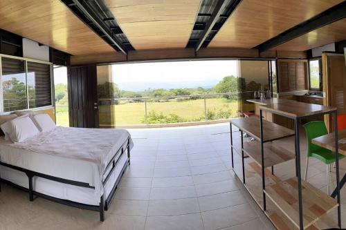 a bedroom with a bed and a kitchen with a large window at Comfortable glamping loft with pool and vineyards in Rivera