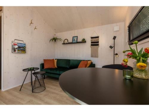 a living room with a green couch and a table at Tiny House Zoutelande near the Beach in Zoutelande