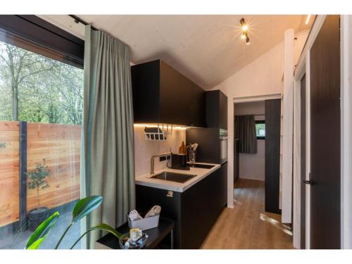 a kitchen with black cabinets and a sink at Tiny House Zoutelande near the Beach in Zoutelande