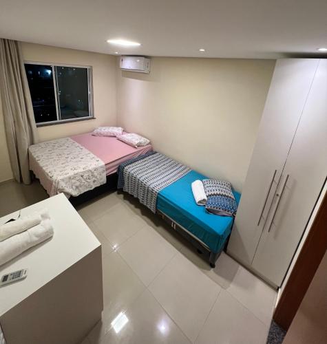 a small room with two beds and a refrigerator at Casa da Dinda in Ilhéus