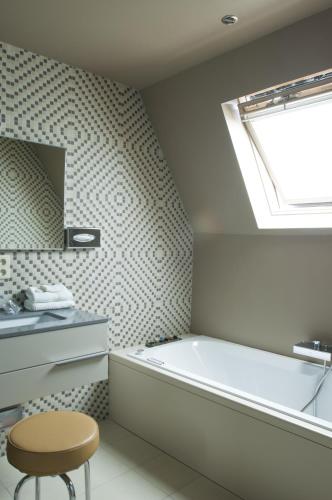 a bathroom with a tub and a window and a stool at Hotel Recour in Poperinge