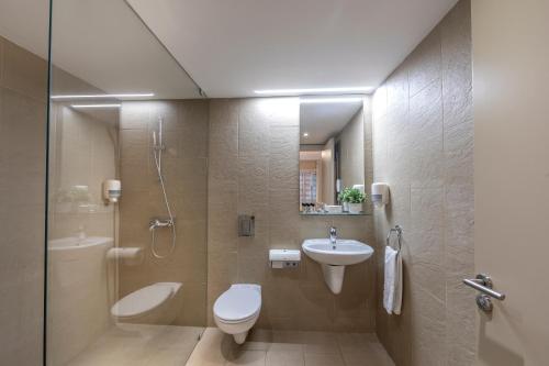 a bathroom with a toilet and a sink and a shower at Almond Business Hotel in Nicosia
