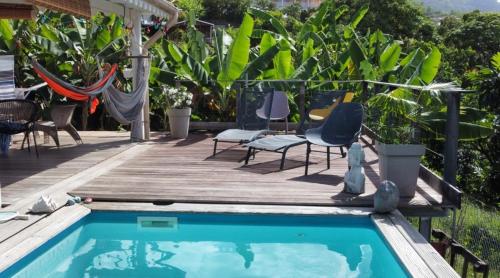 una piscina con sedie e una terrazza in legno di CHARMANT HAUT DE VILLA AVEC PISCINE PARTAGEE a Le Vauclin