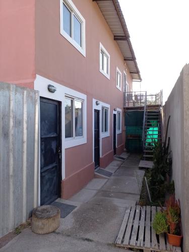 an empty hallway of a pink building with a wooden bench at Tuly in Ciudad Lujan de Cuyo