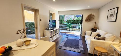 - un salon avec un canapé et une télévision dans l'établissement Grand Terrace With Secret Garden - 4 Bedrooms, à Sydney