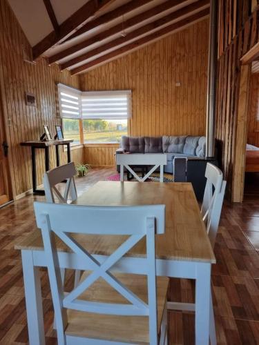 a table and chairs in a living room with a couch at Cabañas Antü Küyen Melipeuco in Melipeuco