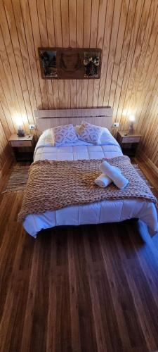 a bedroom with a bed in a wooden wall at Cabañas Antü Küyen Melipeuco in Melipeuco