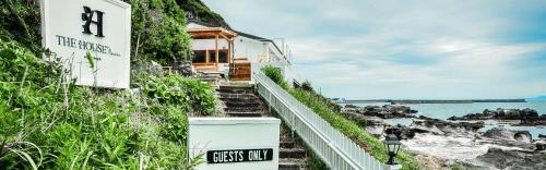 a house on the side of a hill next to the ocean at The House Moroiso secret beach in Miura