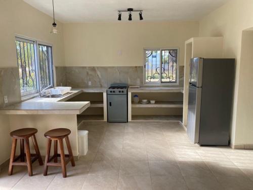 a kitchen with a refrigerator and two stools in it at Los Amores Apartments B in Pérula