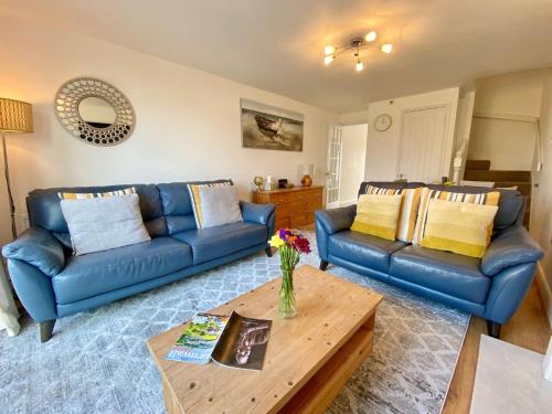 a living room with two blue couches and a table at Heidaway - Padstow in Padstow