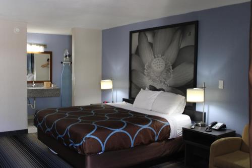 a hotel room with a bed with a large painting on the wall at Super 8 by Wyndham Morganton in Morganton