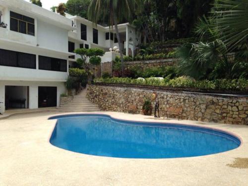 a large blue swimming pool next to a building at Villa Palmitas acogedor departamento nivel piscina gigante jardines in Acapulco