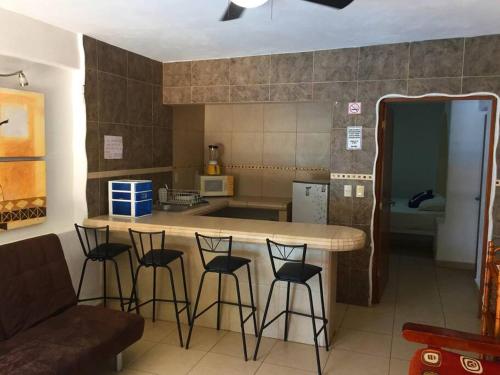 a kitchen with a counter and stools in a room at Villa Palmitas acogedor departamento nivel piscina gigante jardines in Acapulco