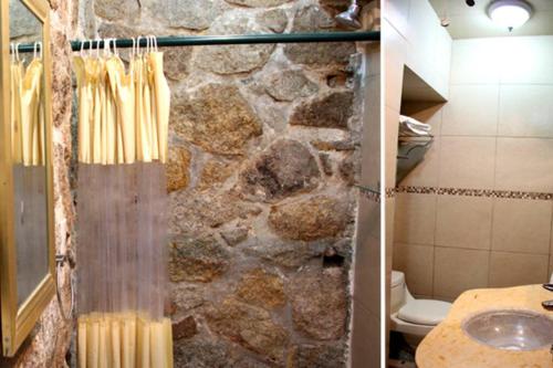 a bathroom with a stone wall and a shower at Villa Palmitas acogedor departamento nivel piscina gigante jardines in Acapulco