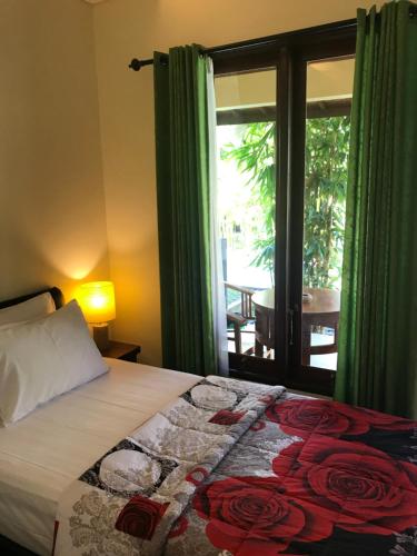 a bedroom with a bed and a window with a patio at Werkudara Guest House in Ubud