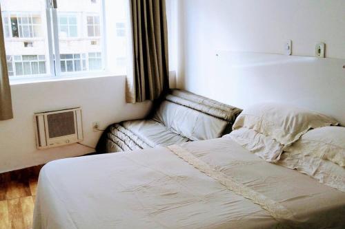 1 cama y 1 sofá en una habitación con ventana en APARTAMENTO COPACABANA saleta, quarto grande com ar cond wi-fi a 2 qds da praia, en Río de Janeiro