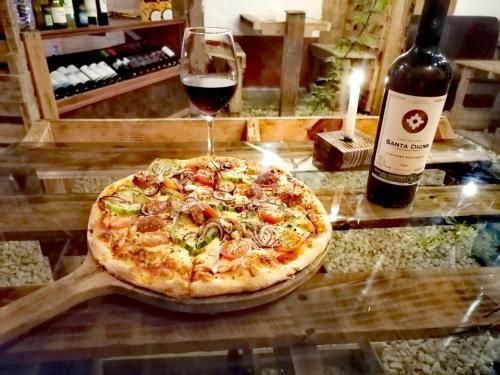 a pizza on a table with a glass of wine at Nature house in Monteverde Costa Rica