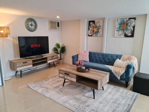 a living room with a blue couch and a tv at Private & Cosy Two Storey Guest House in Guildford