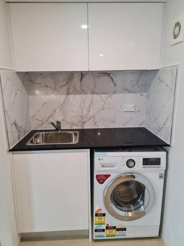 a kitchen with a sink and a washing machine at Private & Cosy Two Storey Guest House in Guildford