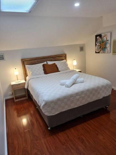 a bedroom with a large bed with white sheets and two lamps at Private & Cosy Two Storey Guest House in Guildford