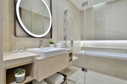 uma casa de banho com um lavatório, um chuveiro e um espelho. em Marriott Executive Apartments Navi Mumbai em Navi Mumbai