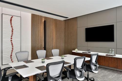 a conference room with a table and chairs and a flat screen tv at Marriott Executive Apartments Navi Mumbai in Navi Mumbai