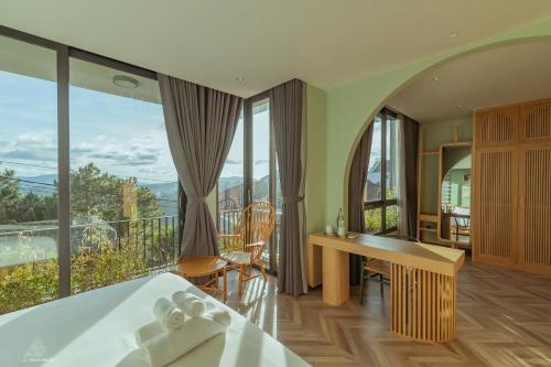 a bedroom with a bed and a desk and a balcony at La Villa Da Lat in Khu Chi Lăng