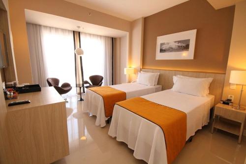 a hotel room with two beds and a window at Linda suíte de hotel, acomoda até 3 pessoas Milly in Rio de Janeiro