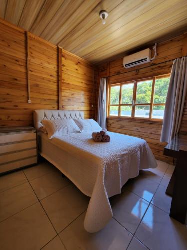 ein Schlafzimmer mit einem Bett in einem Holzzimmer in der Unterkunft Casa em Bombinhas Mariscal in Bombinhas