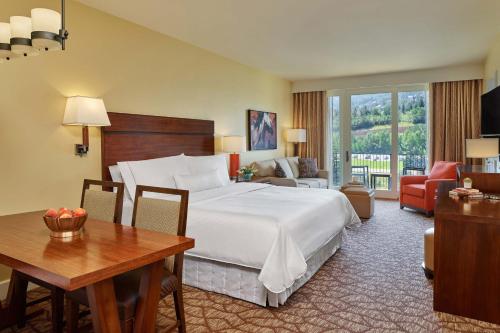 a hotel room with a large bed and a desk and a table at The Westin Riverfront Mountain Villas, Beaver Creek Mountain in Avon