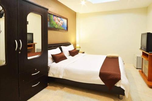 een slaapkamer met een groot bed en een televisie bij the links hotel in Pattaya