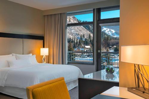 エイボンにあるThe Westin Riverfront Resort & Spa, Avon, Vail Valleyのベッドと大きな窓が備わるホテルルームです。