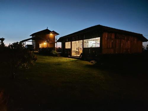 ein paar kleine Gebäude auf einem Feld in der Nacht in der Unterkunft Chalé Rancho Coração Cigano in Araranguá